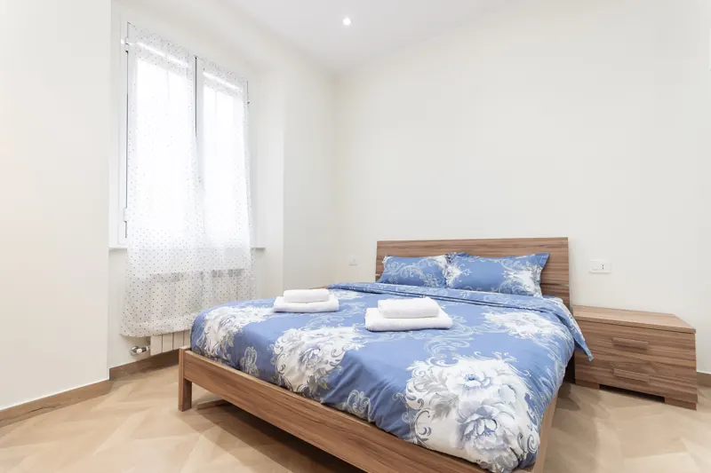 Camera con copriletto blu a fiori e parquet a spina: appartamento in affitto breve a Certosa, Genova gestito da Immobirent, 27.462 € incassati in un anno